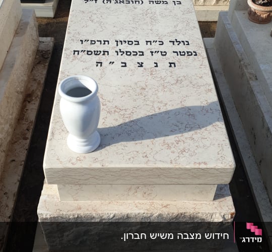מצבות עם כיתוב בעברית ואגרטל לבן על אחת מהן